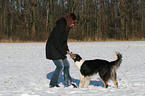 junge Frau spielt mit Border Collie im Schnee