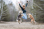 Frau springt mit Hunden in die Luft