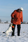 Frau spielt mit Parson Russell Terrier im Schnee