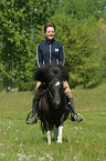 Frau reitet Shetland Pony