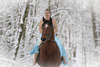 Frau reitet im Kleid durch den Schnee