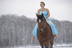 Frau reitet im Kleid durch den Schnee