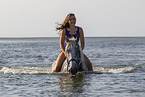 Frau und Lipizzaner-Mix im Wasser